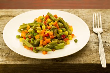 ahşap arka plan üzerinde beyaz tabakta karışık sebze