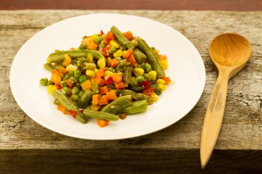 ahşap arka plan üzerinde beyaz tabakta karışık sebze