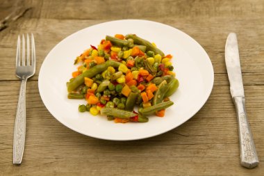 ahşap arka plan üzerinde beyaz tabakta karışık sebze