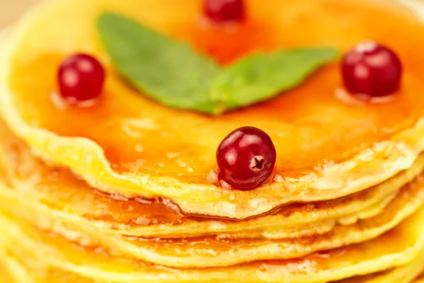A stack of pancakes on a white plate with berries and jam on wooden background — Stockfoto