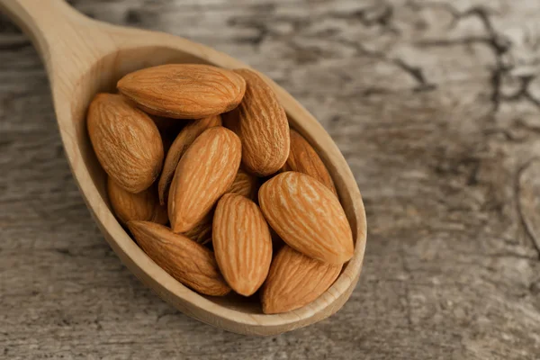 Peeled almonds in spoon on wooden background. For vegetarians — Stock Photo, Image