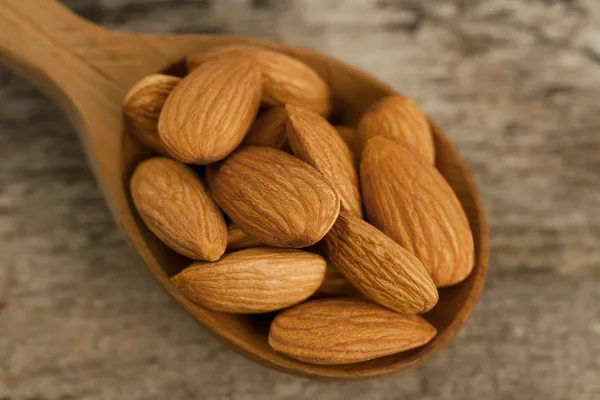 Kupas almond di sendok pada latar belakang kayu. Untuk vegetarian. — Stok Foto