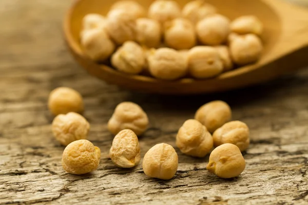 Scattered chickpeas from a jute bag with a spoon on old wooden background — Stock Photo, Image