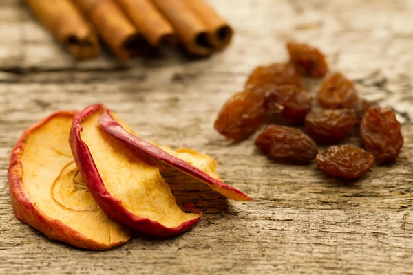 Dried apples with cinnamon sticks and raisins on the old wooden background. Closeup. — Stock Photo, Image