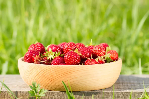 yeşil çayır üzerinde ahşap bir kase taze olgun çilek