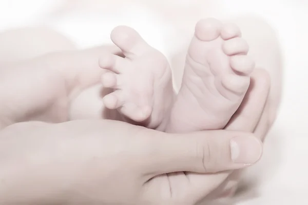 Concepto de amor y familia. manos de madre y pie de bebé —  Fotos de Stock