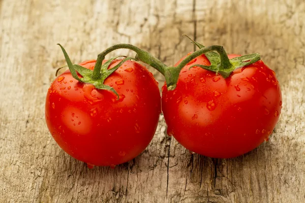 Några röda tomater gren på trä bakgrund — Stockfoto