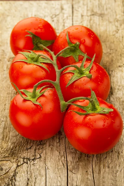 Few red tomatoes branch on wooden background — Stock Photo, Image