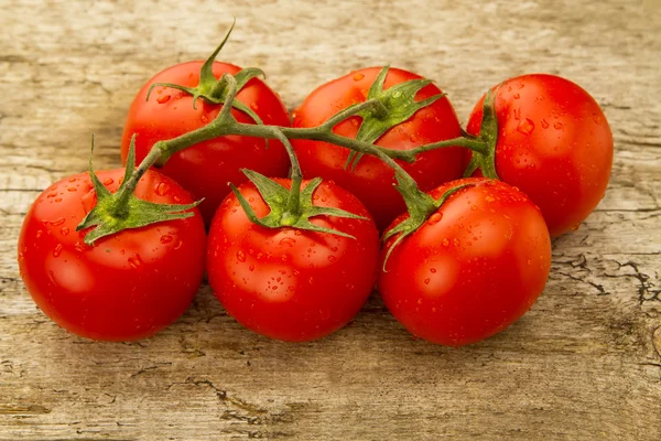 Few red tomatoes branch on wooden background — Stock Photo, Image