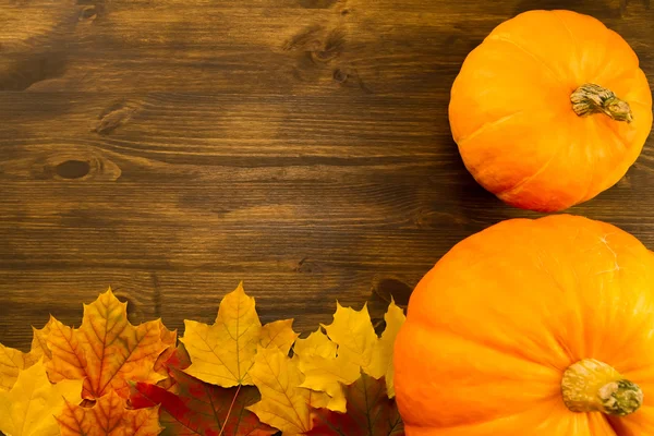 Yellow ripe pumpkin, maple leaves on wooden background. Thanksgiving, autumn. — Stock Photo, Image