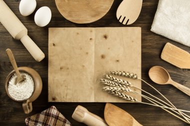 open old vintage book on the aged wooden background. Kitchen utensils, ears of wheat, flour in a pot. homemade, menu, recipe, mock up