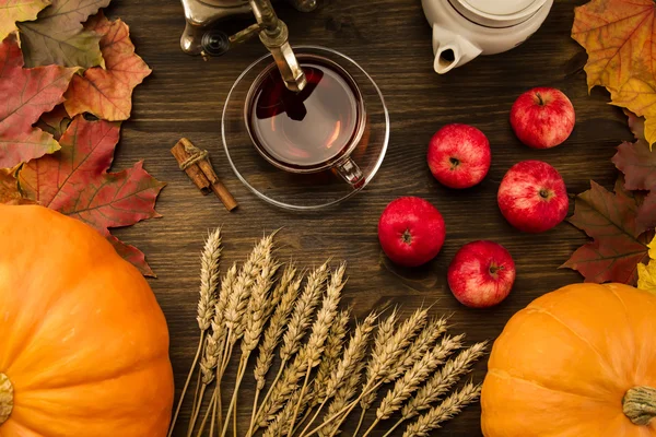 Tea c still life with samovar, apples, ripe orange pumpkins, maple leaves, wheat on wooden background. Thanksgiving, autumn.