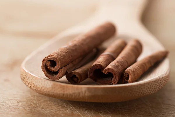 Whole cinnamon sticks in spoon on wooden background — Stock Photo, Image