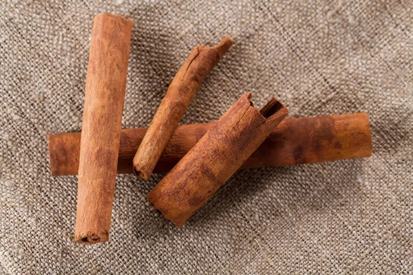 Whole cinnamon sticks on the background of jute fabric — Stock Photo, Image