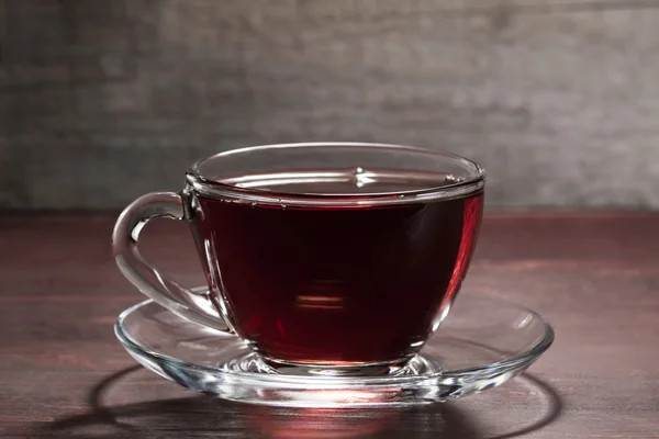 La tasse noire de thé chaud sur la table en bois — Photo