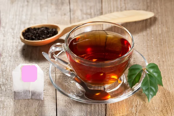 Xícara de chá preto quente com folha na mesa de madeira — Fotografia de Stock