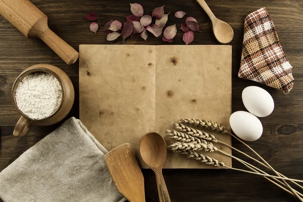 Open old vintage book on the aged wooden background. Kitchen utensils, ears of wheat, flour in a pot. homemade, menu, recipe, mock up — Stock Photo, Image