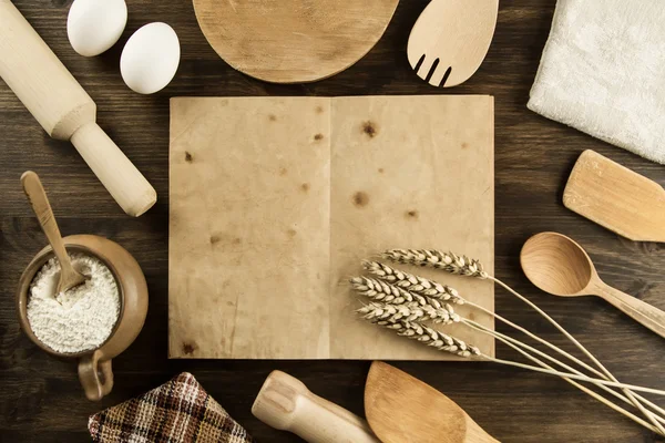 open old vintage book on the aged wooden background. Kitchen utensils, ears of wheat, flour in a pot. homemade, menu, recipe, mock up