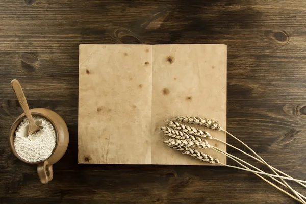 Libro vintage viejo abierto sobre el fondo de madera envejecida. Utensilios de cocina, espigas de trigo, harina en una olla. casero, menú, receta, maqueta — Foto de Stock