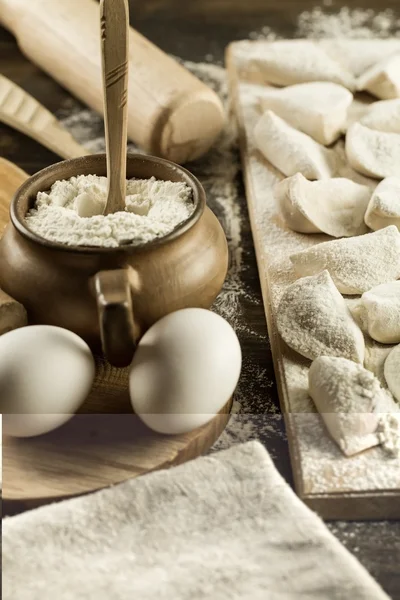 Homemade pasta ravioli over wooden table with flour. kitchen utensils — Stock Photo, Image