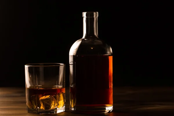 氷と木製のテーブル ボトルでウィスキーのグラス。コニャック、ブランデー. — ストック写真
