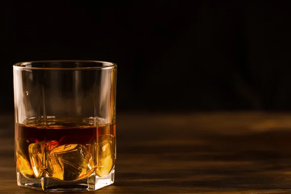 cam ahşap bir masa üzerinde buzlu viski. Konyak, brandy.