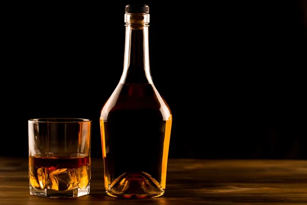 氷と木製のテーブル ボトルでウィスキーのグラス。コニャック、ブランデー. — ストック写真