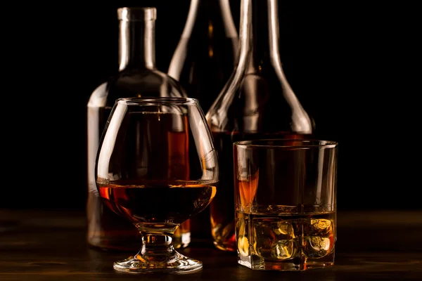 Bardak buz ve ahşap bir masa üzerinde bir şişe viski. Konyak, brandy. — Stok fotoğraf