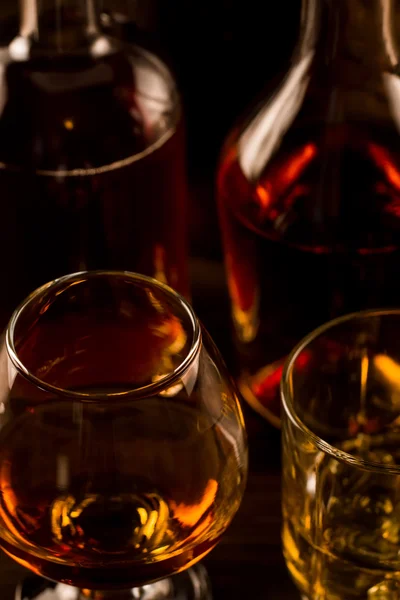 Glazen voor whisky met ijs en een fles op een houten tafel. Cognac, brandewijn. — Stockfoto