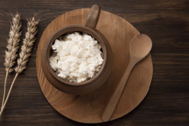 fresh tasty curd in pot on wooden background. Homemade, cottage cheese