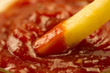 French fries with fresh ketchup and salt in a spoon on a paper bag