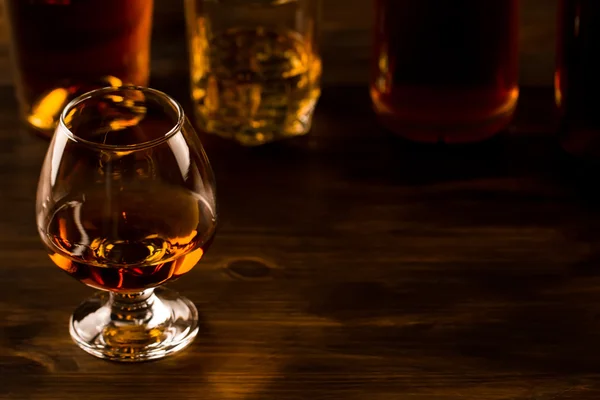 Glas whiskey med is och en flaska på ett träbord. Cognac, brandy. — Stockfoto