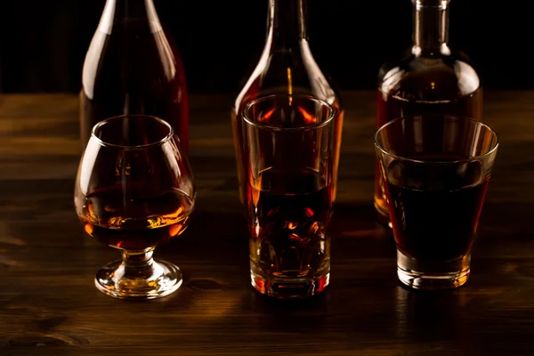 Glazen voor whisky met ijs en een fles op een houten tafel. Cognac, brandewijn. — Stockfoto