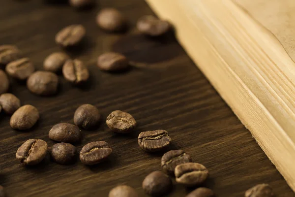 Rostade kaffebönor på gamla vintage öppen bok. Meny, recept, prototyper. Trä bakgrund. — Stockfoto