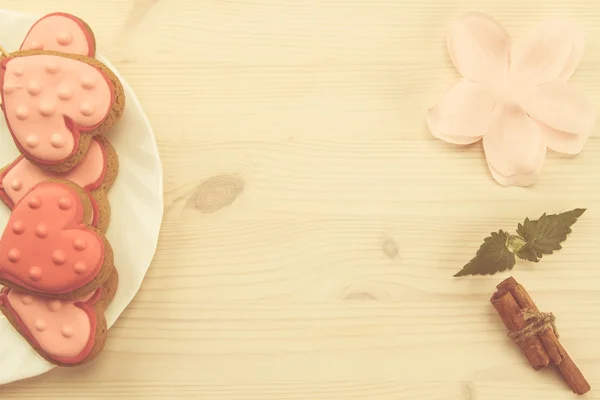 ahşap arka plan üzerinde kalp şeklinde beyaz tabakta lezzetli taze kurabiyeler.