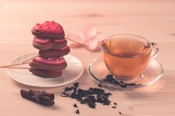 Délicieux biscuits frais en forme de coeur sur une assiette blanche sur fond de bois. Une tasse de thé vert. Petit déjeuner — Photo