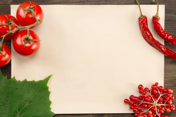 sheet old vintage paper with berries, tomatoes, chili pepper and grape leaves on wooden background . Healthy vegetarian food. Recipe, menu, mock up, cooking.