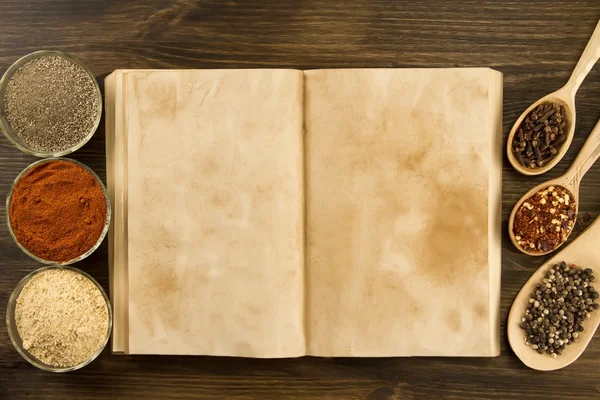Libro vintage viejo abierto con especias sobre fondo de madera. Comida vegetariana saludable. Receta, menú, maqueta, cocina . — Foto de Stock