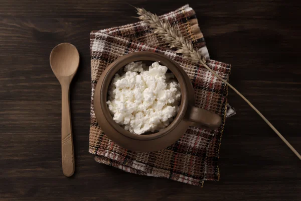 fresh tasty curd in pot on wooden background. Homemade, cottage cheese