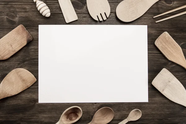 White sheet of paper with utensils on the old wooden background. Mock up — Stock Photo, Image