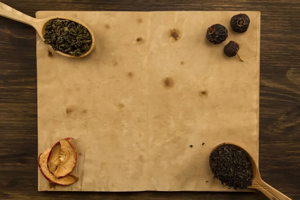 Negro, Oolong en una cuchara, manzanas secas en el viejo libro abierto en blanco sobre fondo de madera. Menú, receta, maqueta — Foto de Stock