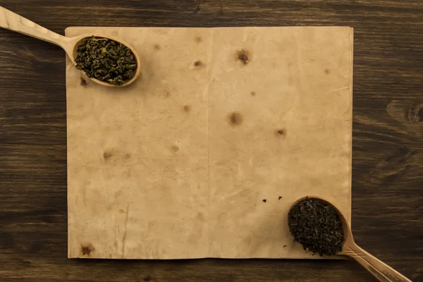 Black, Oolong tea spoon in the old blank open book on wooden background. Menu, recipe, mock up — Stock Fotó