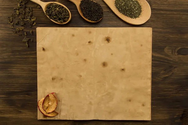 Black, Oolong in a spoon, dried apples on the old blank open book on wooden background. Menu, recipe, mock up — 스톡 사진