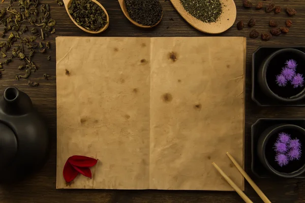 Zwarte theepot twee kopjes thee collectie, bloemen, oude open notitieboek op houten achtergrond. Menu, recipe, mock up — Stockfoto