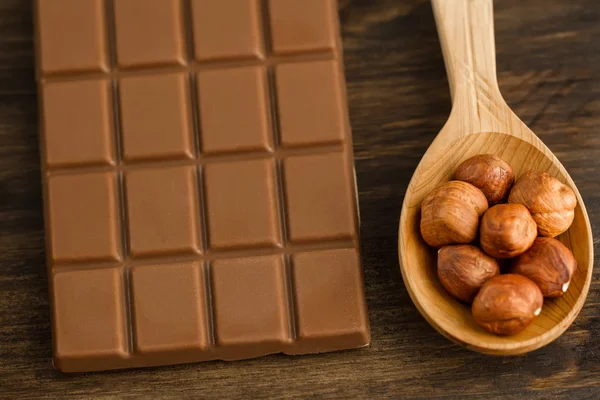 Σοκολάτα και αποφλοιωμένες φουντούκια με κουτάλι σε ξύλινα φόντο — Φωτογραφία Αρχείου