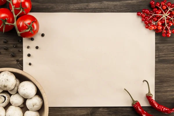 Blatt altes Vintage-Papier mit Tomaten, Champignons, Chilischoten auf gealtertem Holzgrund. gesunde vegetarische Kost. Rezept, Menü, Attrappe, Kochen. Stockfoto