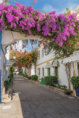 view of a street decorated with bougainvillea in Puerto Mogan, Gran Canaria, Spain clipart