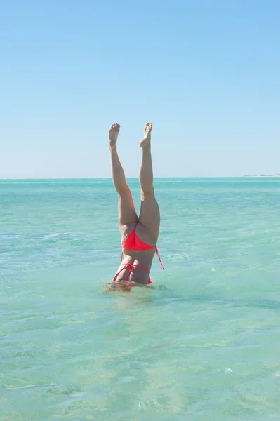 Sporty bikini woman handstand ocean water — Stock Photo, Image