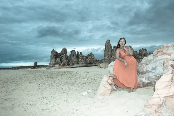 Woman in red dress at beach with dark storm clouds — Stock Photo, Image
