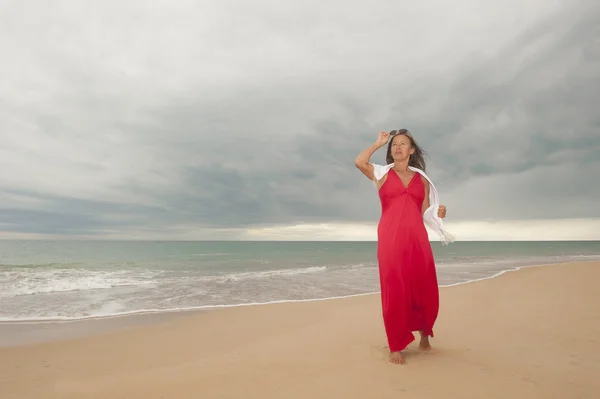 Gelukkig volwassen vrouw aan strand en met drak wolken — Stockfoto